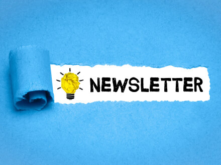 Ein hell·blauer Hintergrund aus Papier. In dem Papier ist ein Loch. In dem Loch steht das Wort: Newsletter. Links vor dem Wort ist eine gezeichnete Glühbirne., Bild © magele-picture / stock.adobe