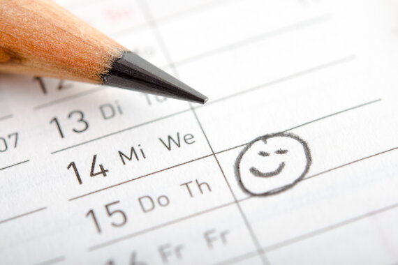 Foto: Ein Kalender und ein Bleistift. Neben einem Datum ist ein Smiley aufgemalt.