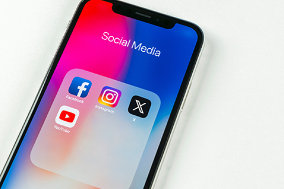Foto von einem Handy mit den Symbolen von: Facebook, Instagram, X und YouTube.