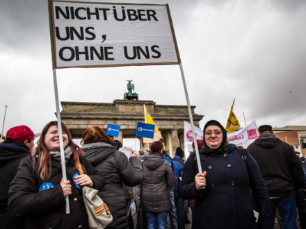Foto von 2 Frauen bei einer Demonstration. Die Frauen halten zusammen 1 Schild hoch. Auf dem Schild steht: Nicht über uns, ohne uns.