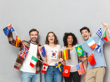 Das Bild zeigt 4 fröhliche junge Menschen. Die Menschen halten 17 kleine Flaggen an einer Schnur in der Hand.