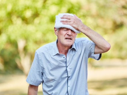 Das Bild zeigt einen alten Mann. Der alte Mann hat Probleme mit dem Kreislauf. Der Mann kühlt seine Stirn mit einem feuchten Tuch.