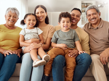 Foto von einer Familie mit Groß·eltern auf einem Sofa.