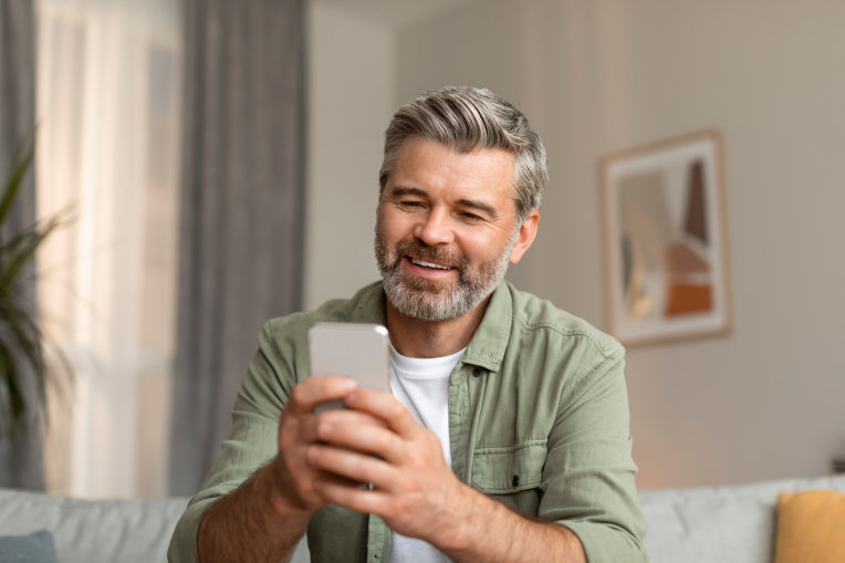 Das Bild zeigt einen lächelnden Mann mit einem Handy.