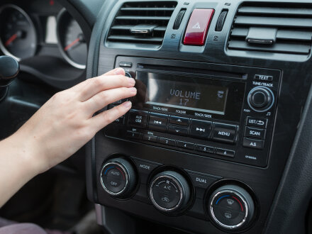 Foto von einer Hand und einem Auto·radio. Die Hand stellt bei dem Auto·radio einen Radio·sender ein., Bild © 4frame group / stock.adobe