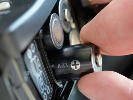 Foto von einer Hand. Die Hand legt neue Batterien in ein elektronisches Gerät ein., Bild © SOLDATOOFF / stock.adobe