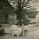 Tochter Maria Schwetz steht mit dem Puppenwagen in der Steinbarackensiedlung.