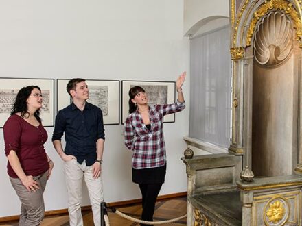 Foto von 3 Personen bei einer Führung. Die eine Person erklärt den anderen 2 Personen etwas., Bild © Uwe Niklas / Stadtmuseum im Fembo-Haus
