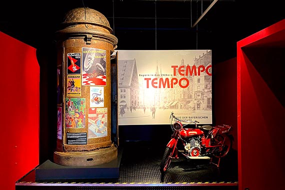 Blick in den Vorraum der Ausstellung mit einer Nürnberger Litfaßsäule, hergestellt um 1905 bei MAN, und einer Ardie Minimax, Baujahr 1920.