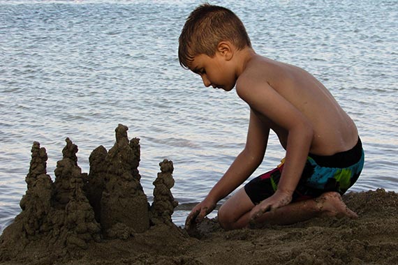 Ein Junge baut eine Sandburg.