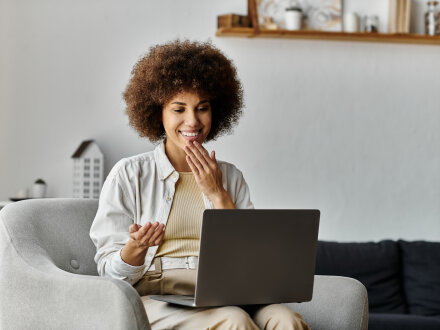 Foto von einer Frau mit einem Laptop auf dem Schoß. Die Frau macht gerade ein Video in Gebärden·sprache., Bild © Bliss / stock.adobe