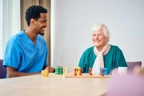Pflegekraft und Seniorin spielen ein Brettspiel