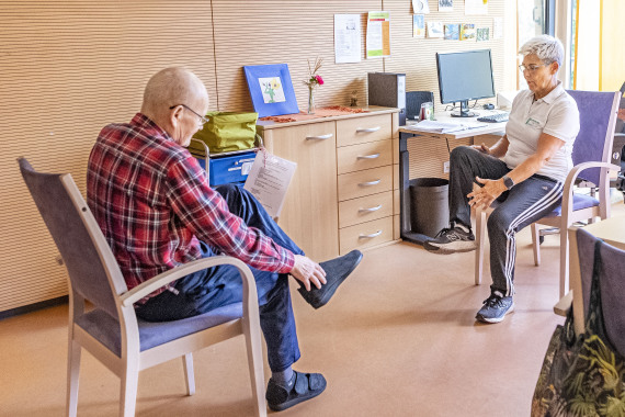 Mitarbeiterin und Senior bei Reha-Übungen