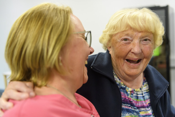 Bewohnerin und Mitarbeiterin lachen gemeinsam