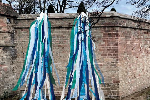 Farbige Bänder hängen von der Burgmauer hinab in den Burggraben