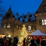 Stände des Weihnachtsmarkts und ein Christbaum im Innenhof von Schloss Almoshof