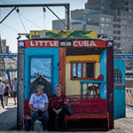 Zwei Frauen sitzen vor einem Container mit der Beschriftung "Little Cuba"
