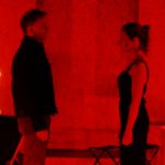 Ein Mann und eine Frau stehen sich in einem roten Raum gegenüber