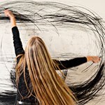 Eine Frau zeichnet mit ausgestreckten Armen Kreise auf eine Wand