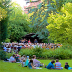 Viele Menschen sitzen auf Decken in einem Park