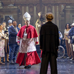 Viele Schauspielerinnen und Schauspiel, darunter ein als Kardinal verkleideter Mann, auf einer Theaterbühne