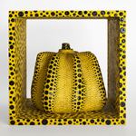 Gelbe, stilisierte Kürbis-Skulptur mit gewölbten Segmenten, überzogen mit schwarzen Punkten in verschiedenen Größen. Der Kürbis steht in einem würfelförmigen Rahmen, der ebenfalls gelb ist und mit schwarzen Punkten bedeckt ist.