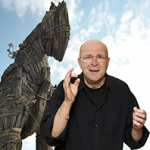 Portrait des Erzählers Michl Zirk vor einer Holzstatue des trojanischen Pferds