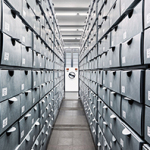 Enger Gang zwischen hohen Regalen mit grauen Archivboxen