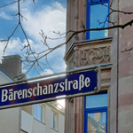 Straßenschild mit der Aufschrift 'Bärenschanzstraße' vor einem Gebäude mit verzierten Sandsteinfassaden