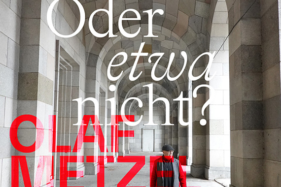 Ein Mann in rotem Mantel und schwarzer Mütze geht unter einem langen, gewölbten Steingang mit großen Bögen