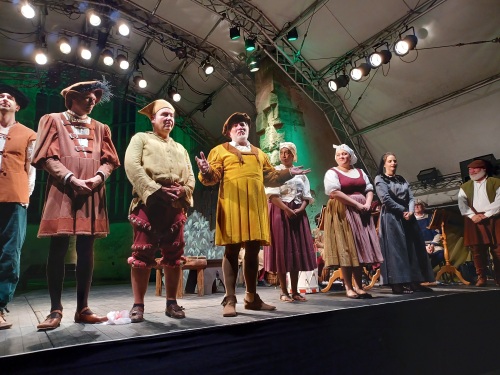 Mittelalterlich gekleidete Schauspielerinnen und Schauspieler stehen auf einer Bühne.