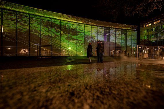 Blick auf die Glasfassade des Neuen Museum Nürnberg mit großflächiger Projektion in Grün