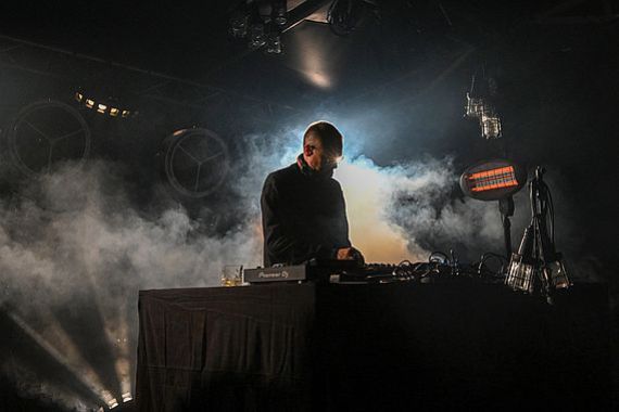 DJ Roman Flügel am DJ-Pult, Nebel steigt auf von hinten