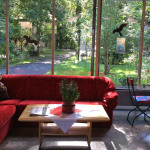 Sofa vor Glasfront, dahinter der Blick in den Garten