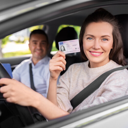 young woman with license and driving school instructor with clipboard in car © lev dolgachov