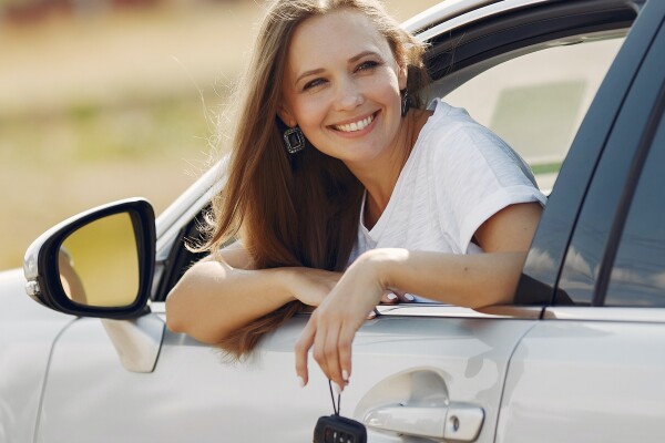 Eine Frau schaut aus einem Autofenster heraus. Sie lächelt.