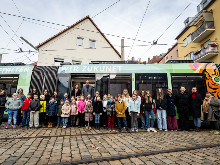 Foto von den Gewinner·kindern und Gewinner·jugendlichen vor der neuen Straßen·bahn.