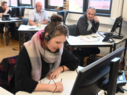 Foto von 4 Personen an kleinen Tischen. Die Personen telefonieren., Bild © Christine Dierenbach / Stadt Nürnberg
