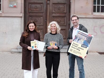 Foto von 3 Personen mit Plakaten vor dem Eingang von der Sperber·schule.