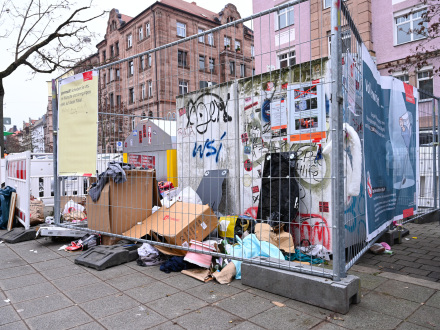 Foto von wildem Müll. Die Stadt Nürnberg hat um den wilden Müll Bau·zäune aufgestellt. An den Bau·zäunen hängen Plakate.