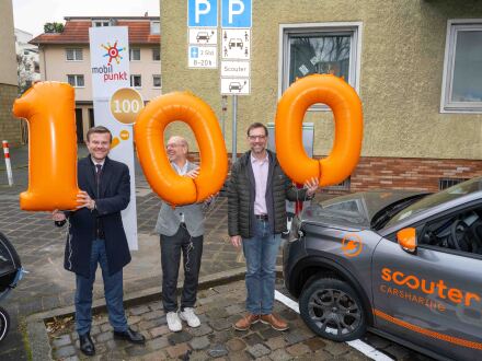 Foto vom Ober·bürgermeister Marcus König, vom Chef von der scouter Carsharing GmbH Thomas Großnann und vom Planungs- und Bau·referent Daniel F. Ulrich bei der Eröffnung vom 100. Mobil·punkt.