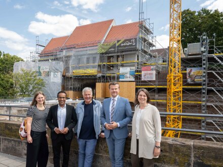 Foto: 5 Personen stehen vor der Stadt·mauer von Nürnberg. Im Hintergrund ist die Bau·stelle vom neuen Kindergarten Emanuel-Wöhrl-Kinder·haus., Bild © Stadt Nürnberg/Christine Dierenbach
