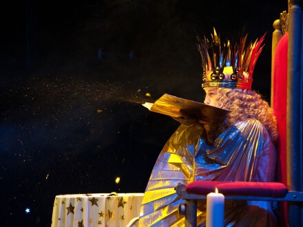 Foto vom Nürnberger Christ·kind. Das Christ·kind pustet Sternen·staub aus seinem Buch voller Weihnachts·geschichten.