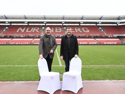 Foto vom Bürgermeister Christian Vogel und dem Ober·bürgermeister Marcus König im Max-Morlock-Sdation. Die beiden stehen am Spiel·feld·rand vor 2 weißen Stühlen., Bild © Christine Dierenbach / Stadt Nürnberg