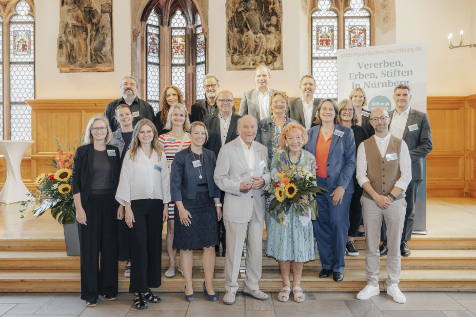 Auf dem Gruppenfoto u. a. zu sehen sind die Partner der Stiftungsinitiative, Margot und Dieter Lölhöffel (Stiftungspreistragende 2025), Elisabeth Ries (Referentin für Jugend, Familie und Soziales der Stadt Nürnberg), Thorsten Brehm (Referent für Finanzen, Personal und IT der Stadt Nürnberg) sowie Projektkoordinatorinnen und -koordinatoren von Degrin e. V., dem Angehörigen- und Demenzberatung e. V. und dem Aktivspielplatz Gostenhof., Bild © Giulia Iannicelli