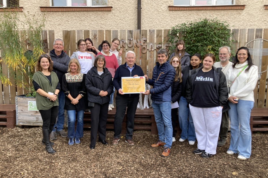 Am Mittwoch, 29. Oktober 2025, wurde die diesjährige Aufwandsentschädigung für die ehrenamtliche Arbeit des Naturschutzbeirats an die Scharrer-Mittelschule gespendet in Anwesenheit von Britta Walthelm, Referentin für Umwelt und Gesundheit (vordere Reihe, 3. v. links) und Mitgliedern des Naturschutzbeirats: Dr. Christian Kölling, Schutzgemeinschaft Deutscher Wald e. V. (2. v. links), Jochen Loy, Bayerischer Bauernverband (in der Mitte mit Schild), Rainer Edelmann, Bund Naturschutz, Kreisgruppe Nürnberg (2. v. rechts), Markus Philipp, Rektor der Scharrer-Mittelschule (Mitte rechts),und Vertreterinnen und Vertreter des Kollegiums und der Schülerschaft.