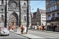 Bild Straßenbahn-Haltestelle vor der Lorenzkirche. Früher fuhren noch Autos und Straßenbahnen durch die Karolinenstraße. Rechts am Rand das Duda-Eck, ein beliebter Treffpunkt in der City. Zwischen Kirche und Duda-Eck sieht man das Gebäude der Commerzbank. Foto Hochbauamt, um 1954. (StadtAN A 55 Nr. I-18-3-3)