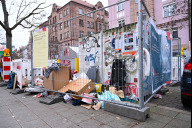 Bild Kampagne gegen illegale Müllablagerung: Ein vermüllter Containerstandplatz ist mit Bauzäunen abgesperrt, auf denen aufklärende Plakate angebracht sind.