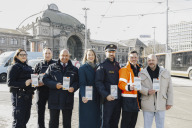 Bild Sozialreferentin Elisabeth Ries (Mitte) bei der Vorstellung der mehrsprachigen Flyer zusammen mit Rainer Brandl, Polizeioberkommissar der Polizeiinspektion Nürnberg-Mitte (3. v. re.), Marius Lang, Verkehrsmeister der Servicedienste der VAG Verkehrs-Aktiengesellschaft Nürnberg (2. v. re.), weiteren Vertretern der VAG und des Außendiensts der Stadt Nürnberg.