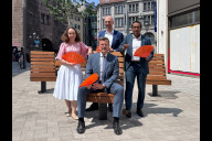 Bild Der erste Bauabschnitt der Breiten Gasse ist am Freitag, 31. Juli 2026, der Öffentlichkeit übergeben worden. Von links: Die Referentin für Wirtschaft und Wissenschaft, Dr. Andrea Heilmaier, Oberbürgermeister Marcus König, 2. Bürgermeister Andreas Krieglstein und 3. Bürgermeister Dr. Nasser Ahmed freuen sich über die neuen Sitzgelegenheiten und die sichtbar bessere Aufenthaltsqualität des fertig gestellten Bauabschnitts zwischen Jakobsplatz und Färberstraße. 